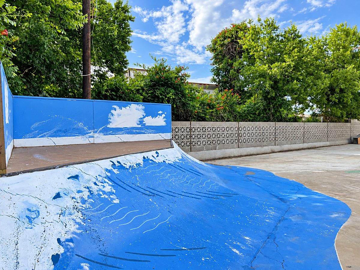 Ramp with blue wave mural beside a breeze-block wall