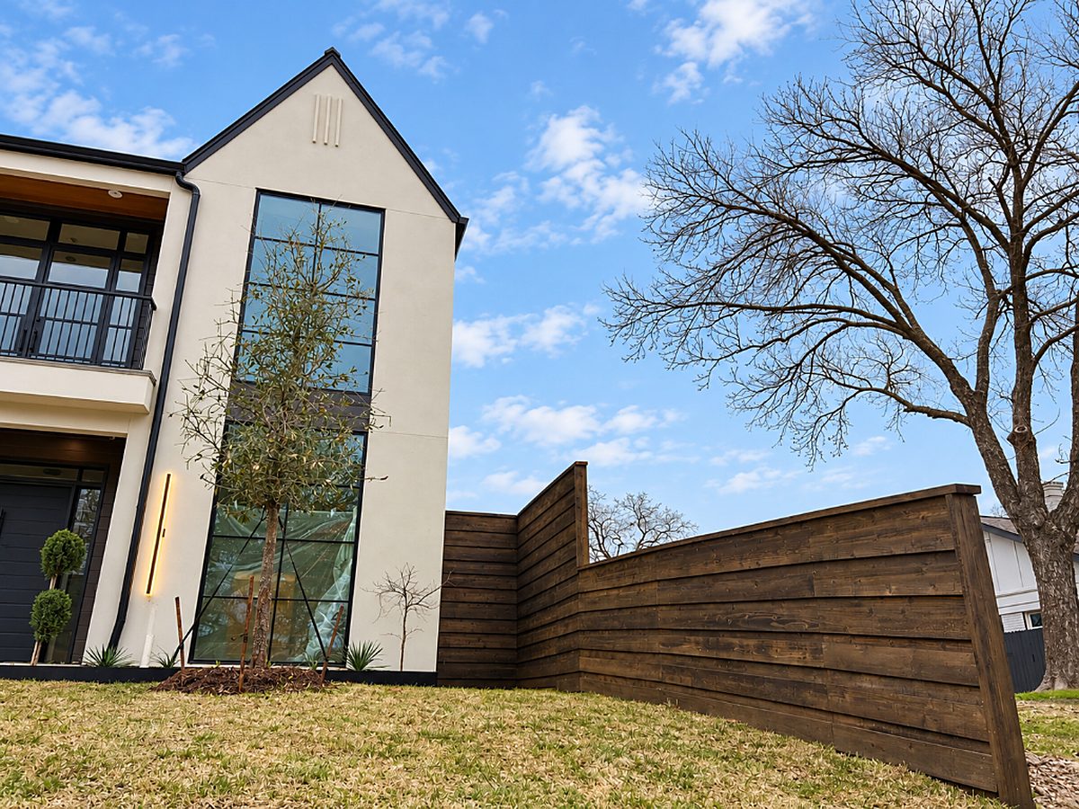 Modern home framed by a dark-stained horizontal wood privacy fence built by Texas 1st Services